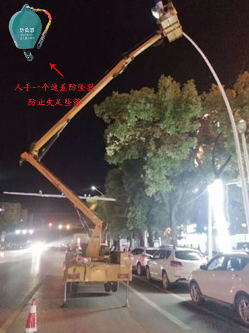夜晚工人站在升降平臺車(chē)上進(jìn)行路燈更換